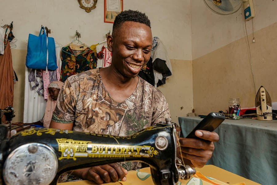 A tailor checking his phone at his sewing machine